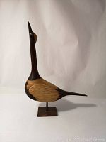Full view of carved wood bird sculpture mounted on wooden base, showing side profile.