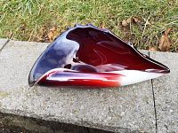 Side view of the red and white art glass shell sculpture capturing its glossy surface and swirling colors.
