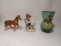 Photo of entire lot showing the Bitossi clown jug, the German Boy with Dog figurine, and unmarked horse figurine side by side on a white surface.