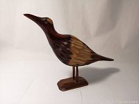 Side view of the carved wooden bird sculpture showing length, detailed wings and beak.