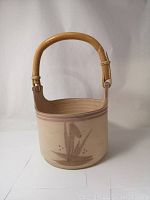 Front view of the signed studio pottery basket showing the pink floral design and bamboo handle.