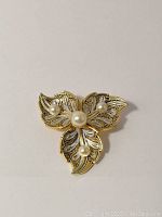 Front view of the leaf brooch showing gold and silver tones with pearl accents.