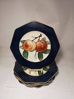 Stack of 7 octagonal plates with navy blue rim and peaches design at center