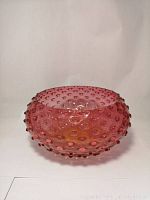 Full side view of the amberina hobnail art glass bowl showing round shape and glossy finish.