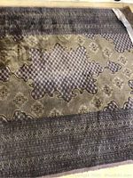 Close-up photo showing the central Bokhara medallion design and intricate patterning of the wool rug with muted earthy tones.