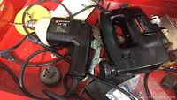 Photo showing Black & Decker 3/8" drill with cord, and black corded jigsaw placed together with assorted accessories.