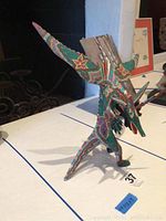 Side view of the wooden Oaxaca dragon figurine showing detailed color patterns and wing structure.
