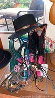 Photo showing black and pink western boots, black hat on stool, green purse, belts, and bolo ties