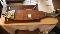 Full view of the large fish-shaped wooden cutting board with metal fish head and tail details.