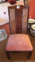 Front view of one armless side chair showing cane back, carved medallion and upholstered seat