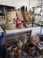 Photo showing brass eagle figurine, angel figurine, white bird figurines on pedestal, miniature plant stand, and assorted collectibles on a metal shelf.