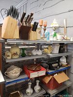 Three shelves with various kitchen and decorative items including knife blocks, candle holders, lamp, and canisters.
