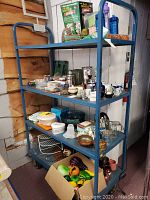 Photo of green metal shelving unit with multiple kitchen and decor items showing entire lot contents.