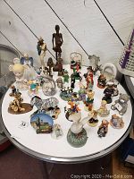 Overview of many figurines arranged on a round white table showing a mix of characters including Don Quixote, clowns, zebra, religious, Christmas, and animals.