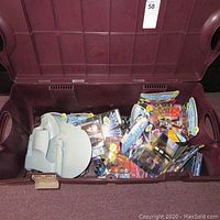Open plastic bin containing Star Trek collectible cards, magazines, comic books, figure packs, and a starship model toy.