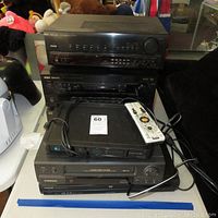 Photo showing all five devices stacked including Samsung VCR, Toshiba and Hitachi DVD players, RCA and Pioneer receivers. Remote control placed on top device.