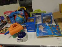 Overview of lot showing various educational toys and games including a Vtech globe, Brain Benders wooden puzzles, boxed science kits, and assorted toys on a white table.