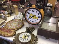 Image showing the Garfield twin bell alarm clock, ornate round clock with Roman numerals, Coca-Cola themed clock, and an ornate circular clock.