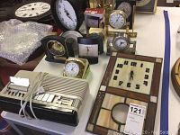 Photo showing multiple desk clocks in various styles including round clocks, square stained glass clock, and a bundled electronic clock radio.