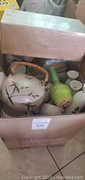 Box with tea pot, green sake bottle, white cups, and other ceramic items