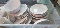 Stoneware pieces stacked in groups showing variety of plates, bowls, mugs, and serving items.