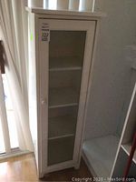 Full view of white cabinet with glass door closed, showing front and side.