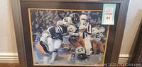Framed football action photo showing Steelers players with signature on image.