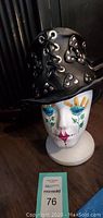 Front view of the foam mannequin head wearing the decorated black leather hat with studs and lacing.