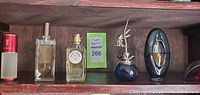 Wide view showing six perfume bottles on dark wood shelf