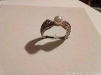 Front view of the ring showing the central faux pearl and silver band with hematite stones