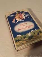 Photo showing the front cover of the book with a colorful illustration of a figure riding a horse labeled 'Tales from the Arabian Nights'