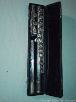 Full view of vintage Roth silver flute model 15244 disassembled into three parts (head joint, body, foot joint) resting in black hard case with interior lining.