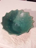 Top and inside view of green glazed pottery bowl showing ruffled edges and speckled finish.