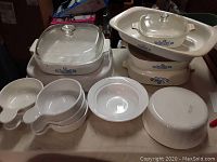 15-piece vintage CorningWare cookware and serving set with blue cornflower pattern and glass lids, displayed on a tabletop.