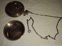 Open case showing inner movement with chain laid out