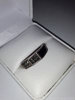 Photo showing the ring inside a white cushioned jewelry box with clear view of the onyx and hematite stones and silver band.
