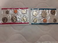 Two 1979 US Mint coin sets with six coins each, including Susan B Anthony and Kennedy coins in original plastic packaging.