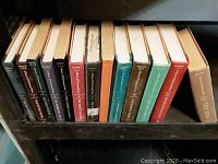 Spine view of 13 books all part of A Series of Unfortunate Events showing author Lemony Snicket and volume numbers 1-13