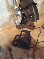 Close-up of the trimmer motor housing and battery pack connected, showing the device in a resting position indoors.