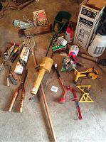 Overview of vintage AGWAY crop duster spreader with various assorted garden tools and sprayers arranged on concrete floor.