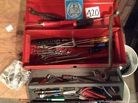 Full open red metal toolbox with assorted hand tools inside