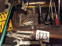 Photo showing assortment of hand tools including wrenches, screwdrivers, pliers and yellow Stanley tool bit set along with metal toolbox tray.