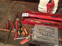 Overview of assortment showing metal toolbox tray, screwdrivers, pliers, hacksaw, pipe cutter, crowbar and socket set in plastic case.