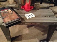 Photo showing the full Craftsman metal router table with ribbed surface standing on four metal legs, next to the boxed bearing kit placed on the table.