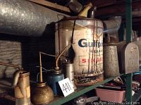 Wide shot showing large Gulfpride gas can and several vintage oil cans on a shelf with some rust and wear visible.