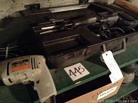 Photo showing the Skil 1/4 inch drill in light gray with orange label, some wear marks and writing, placed on a table next to a case.