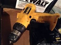 Close-up of yellow DeWalt 3/8 inch cordless drill with black chuck and some visible wear.