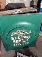 Front view of green metal door with embossed text and logo on vintage cabinet.