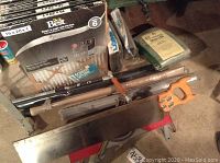 Image shows multiple Aire Best furnace filters stacked, hand saw, metal screen frame and screen mesh rolls.