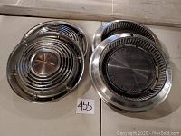 Two pairs of Oldsmobile hubcaps shown side by side, highlighting different designs and the overall condition of the hubcaps.